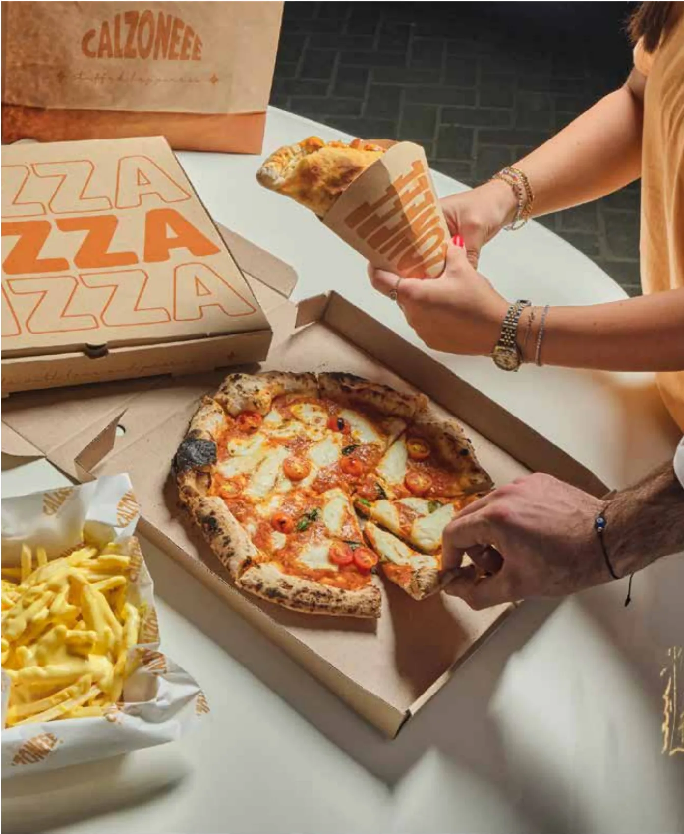Guest serving a slice from an open pizza box