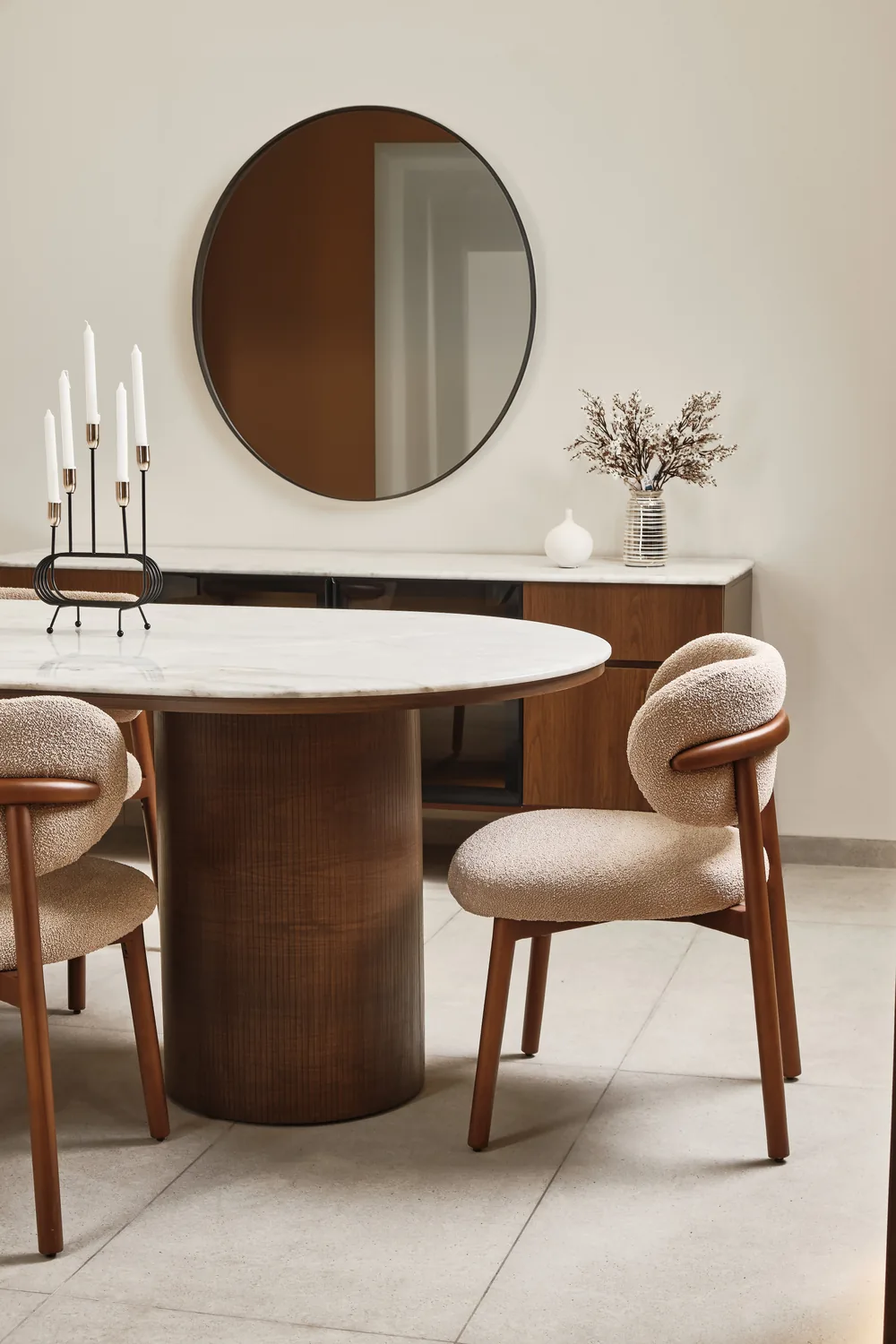 Round dining table with boucle chairs and a wall mirror