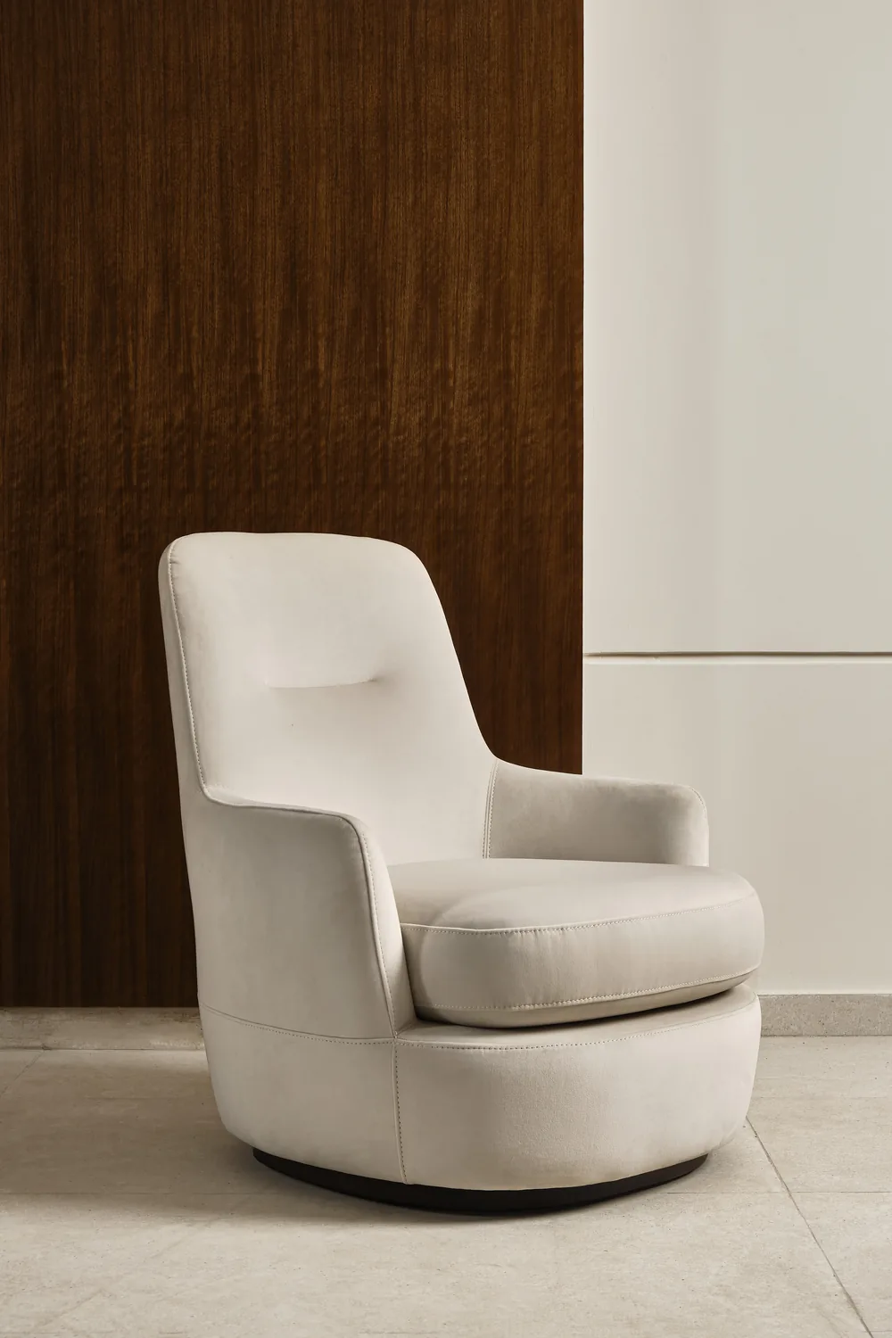 Cream swivel armchair against a walnut wall